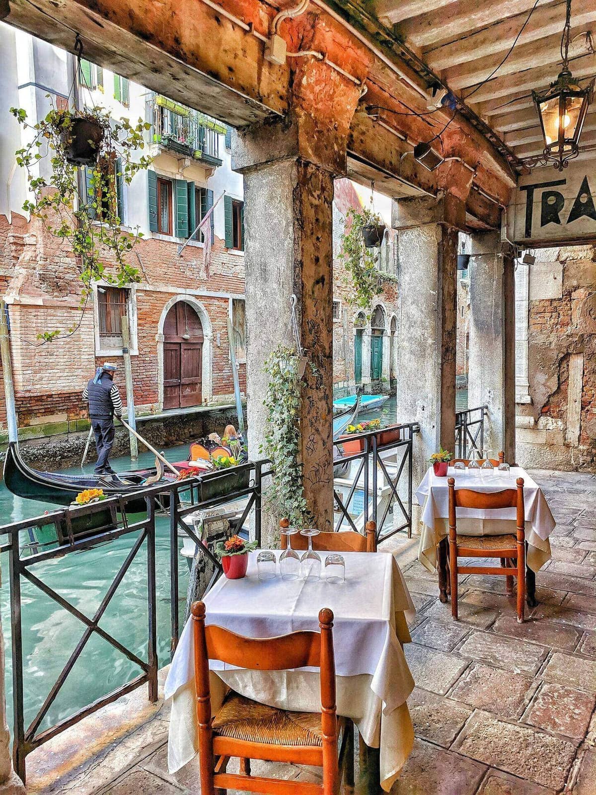 A working boat moves through a Venice canal in low afternoon light, vaporetto stop in the distance.
