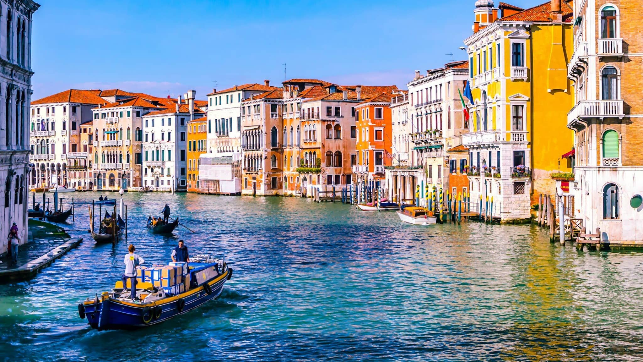 Interior of a Venice flat with tall windows opening on a quiet calle in the morning.